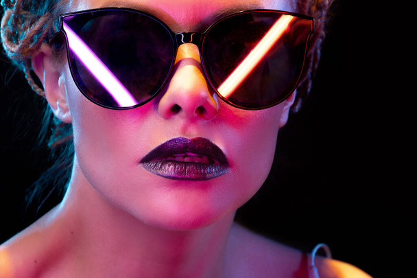 Neon style, reflection of neon lamps in dark glasses of a young stylish woman, - Fotografie, Obrázek