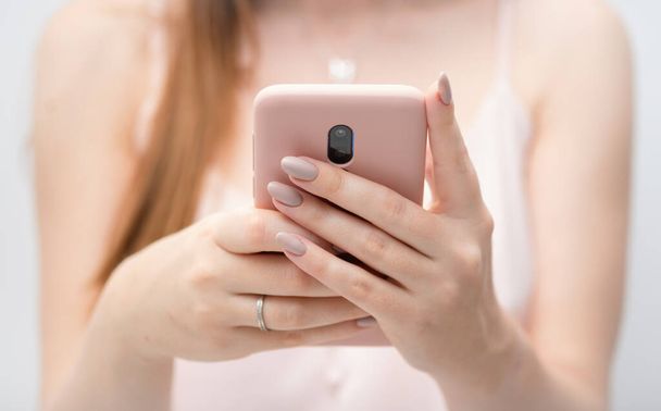 Девушка руки молодая женщина, используя розовый случай смартфон социальные сети, проверяя новости, играя в мобильные игры или смс-ки крупным планом. Блогинг гаджетов - Фото, изображение