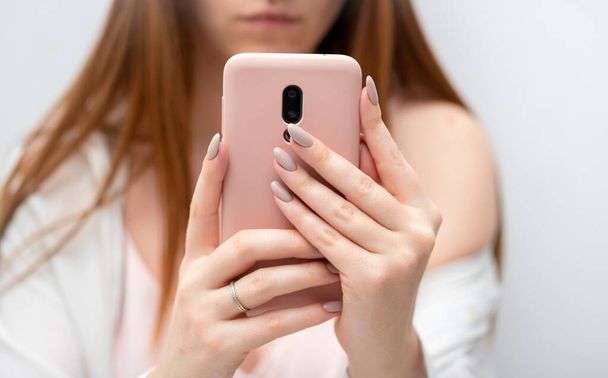 Weibliche Hände junge Frau mit rosa Hülle Smartphone Social Media, Nachrichten checken, spielen Handyspiele oder SMS aus nächster Nähe. Gadget-Blogging - Foto, Bild