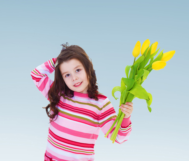 Adorable little girl holding a bouquet of yellow tulips. - Fotoğraf, Görsel