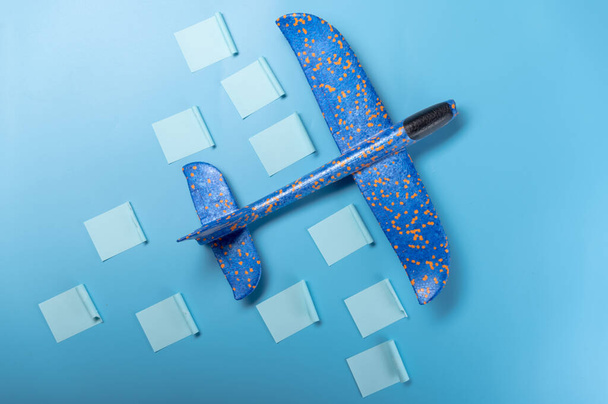 Самолет и наклейки с заданиями. Детский самолет на синем фоне. Наклейки с заданиями на столе. Вид сбоку. - Фото, изображение