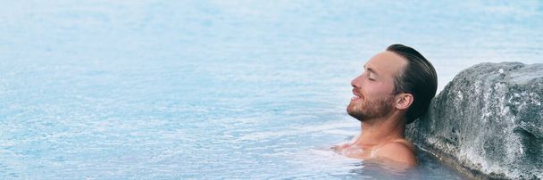 Wellness Spa man relaxing in hot springs outdoor at luxury resort spa retreat. Handsome young male model with eyes closed resting in natural water pool on travel vacation holiday. banner background. - Zdjęcie, obraz