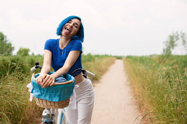 Sexy woman with vintage bike in a country road. - 写真・画像