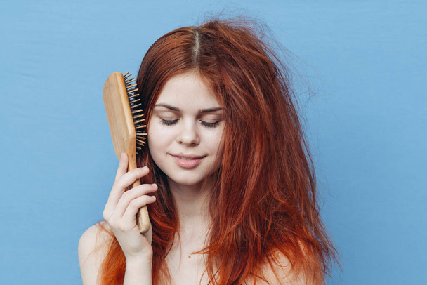 pretty woman combing naughty hair blue background - Foto, Imagem