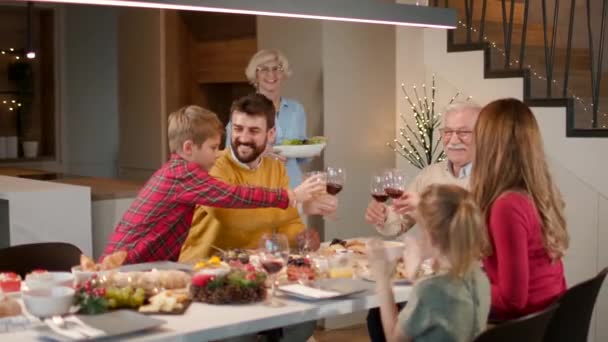 Šťastná rodina večeří s červeným vínem doma - Záběry, video