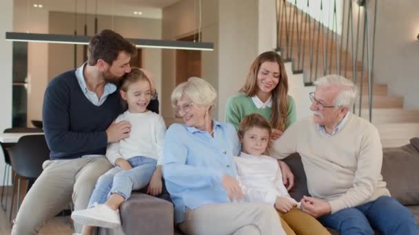Famiglia multi generazione seduta insieme sul divano di casa - Filmati, video
