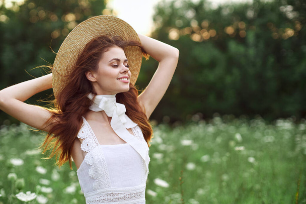 beautiful woman in a hat in a field with flowers walk - Fotó, kép