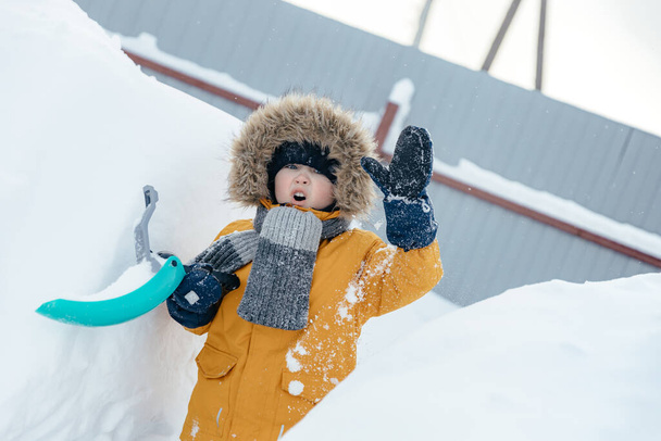 Beş ya da altı yaşındaki sevimli küçük çocuk sokakta yürürken oyun oynarken eğleniyor. Çocuklar için kış açık hava aktiviteleri. - Fotoğraf, Görsel