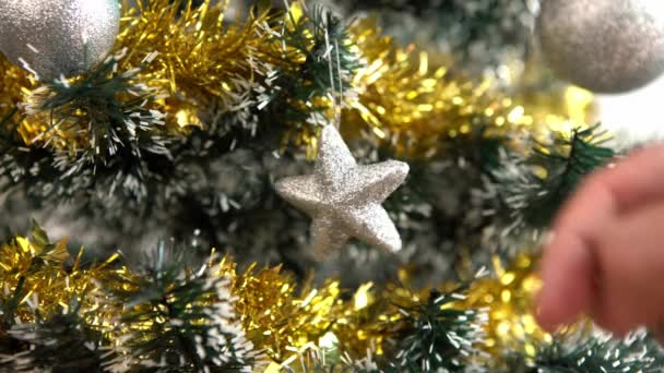 Merry christmas and happy holidays, hand of a man is decorating the spruce tree indoors home at winter. Xmas stars hanging of fir branches for decoration banner, New Year concept. - Footage, Video