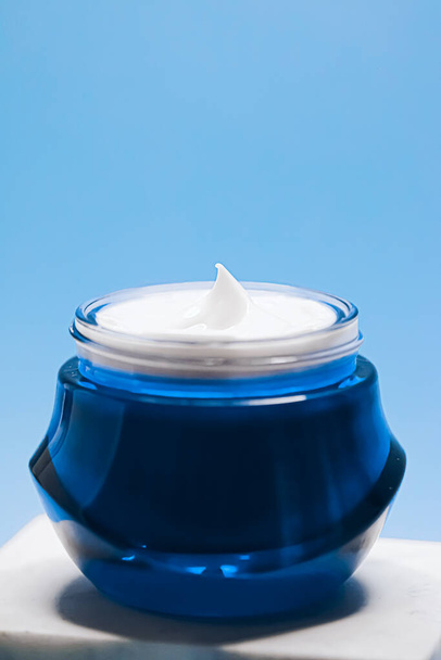Cuidado de la piel antienvejecimiento y cosméticos, crema facial de belleza en frasco sobre fondo azul - Foto, Imagen
