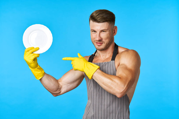 Dishwasher rubber gloves plate in hands blue background - Фото, изображение