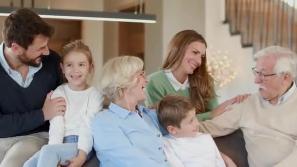 Πολυδύναμη οικογένεια κάθεται μαζί στον καναπέ στο σπίτι - Πλάνα, βίντεο