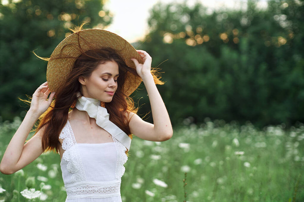 beautiful woman in a hat in a field with flowers walk - Фото, изображение