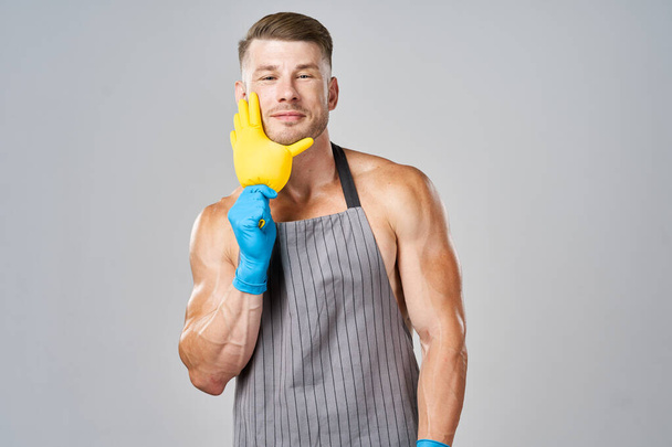 pumped up man in apron rubber gloves cleaning housework - Fotografie, Obrázek