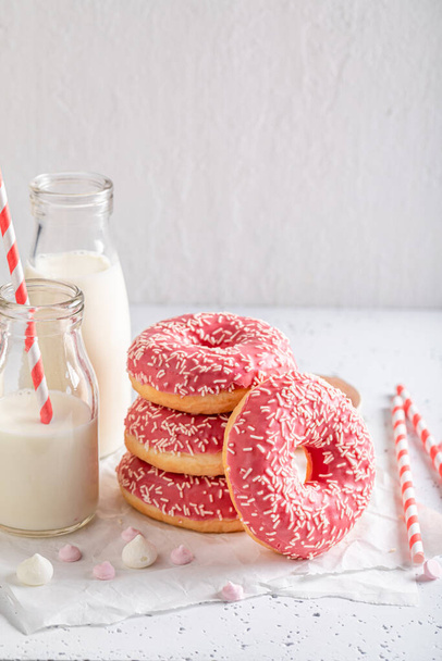 Tasty pink donuts as takeaway dessert. Served with milk. Donates best taste with milk. - Фото, зображення