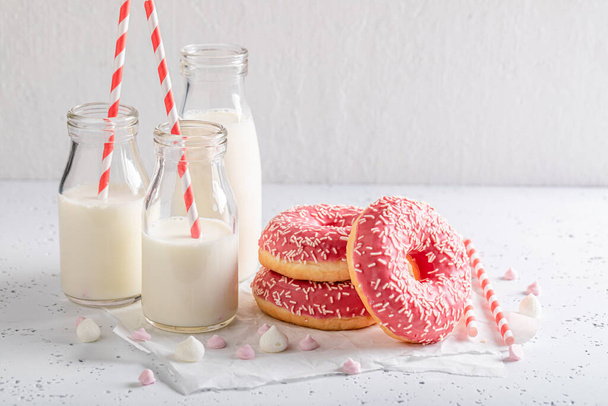 Delicious pink donuts with sprinkles and glaze. Served with milk. Donates best taste with milk. - 写真・画像