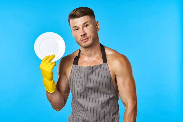 Dishwasher rubber gloves plate in hands blue background - Photo, image