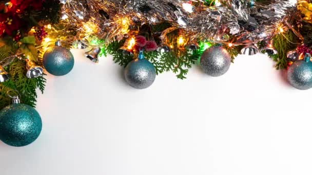 Rámeček zelené borovice s vánoční kuličky, lesklý tinsel, světla a hadovité na bílém pozadí a prostor pro text. Horní pohled na jedle větve stromů a vánoční dekorace banner a novoroční koncept - Záběry, video