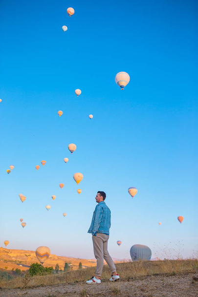 Ευτυχής άνθρωπος κατά τη διάρκεια της ανατολής βλέποντας αερόστατα θερμού αέρα στην Καππαδοκία της Τουρκίας - Φωτογραφία, εικόνα
