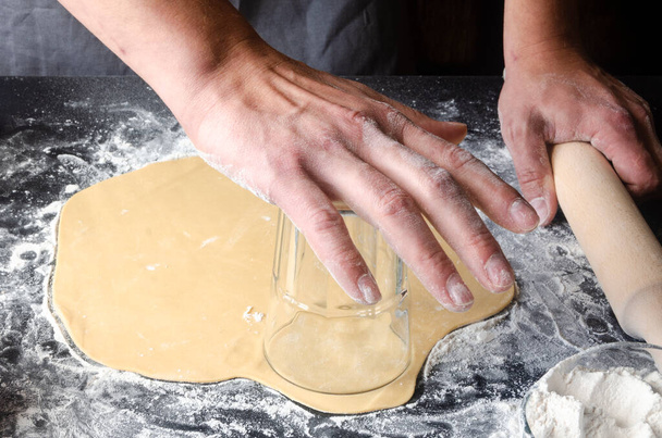 Man kneading dough on board sprinkled with flour. Ingredients for the dough - Φωτογραφία, εικόνα