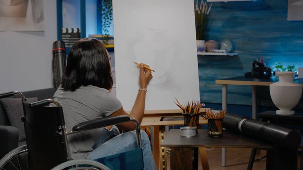 Μαύρος καλλιτέχνης με χάντικαπ χρησιμοποιώντας μολύβι σε καμβά - Φωτογραφία, εικόνα