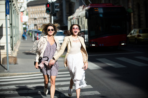 Two excited happy women walking running together on the street. Funny vacation, romantic travel. - Foto, imagen