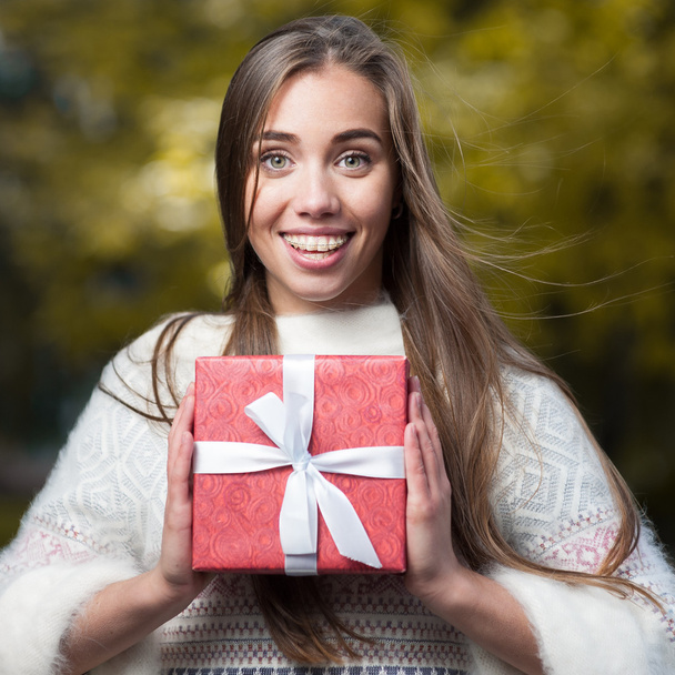 привлекательная молодая женщина держит красный подарок
 - Фото, изображение