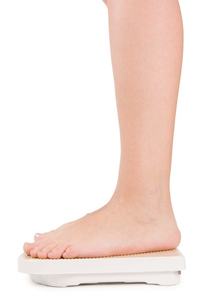 Female feet on scales isolated on white - Photo, image