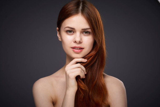 pretty red-haired woman naked shoulders posing dark background - Valokuva, kuva