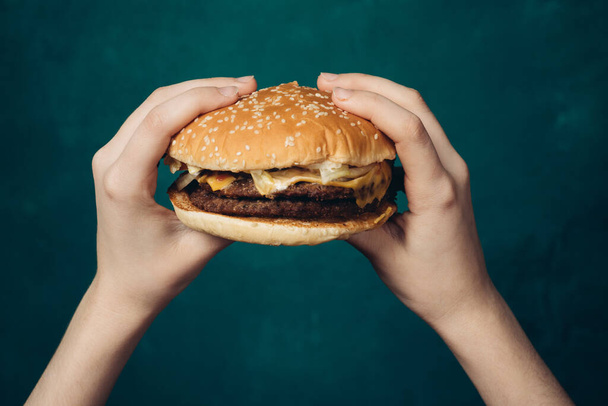 hamburger in hands close-up fast food green background - Φωτογραφία, εικόνα