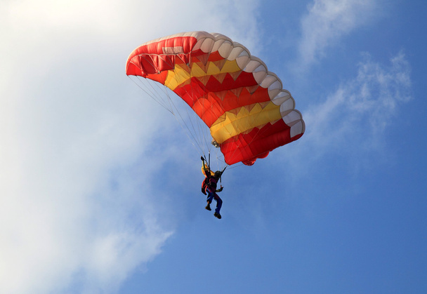 Paraquedas de vela amarelo e vermelho no céu azul
 - Foto, Imagem
