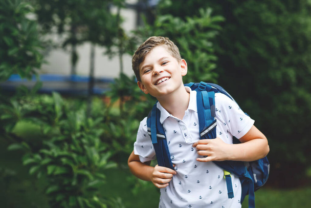 Boldog kisfiú táskával, sétál. Középiskolás vagy középiskolás. Izgatott gyerek az iskola udvarán. Vissza az iskolába.. - Fotó, kép