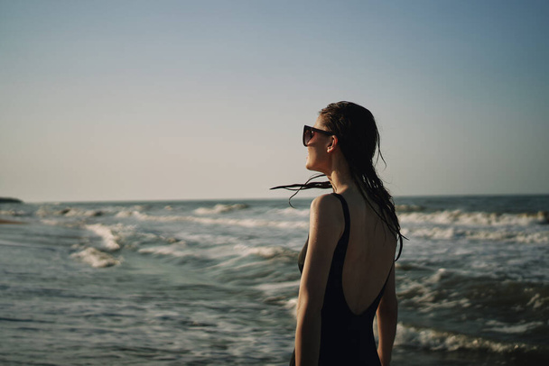 woman in black swimsuit walking on the beach ocean summer - Fotó, kép