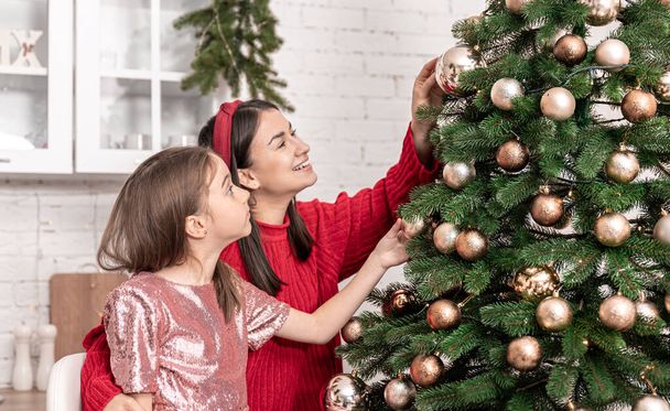 Mom and little daughter decorate the Christmas tree together. - Foto, Imagen