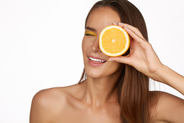 Beautiful sexy young woman with perfect healthy skin and long brown hair day makeup bare shoulders holding orange lemon grapefruit healthy eating organic food diet weight loss - Photo, image