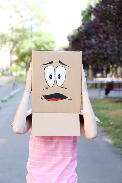 γυναίκα με κουτί από χαρτόνι στο κεφάλι της με το θλιμμένο πρόσωπο, σε εξωτερικούς χώρους - Φωτογραφία, εικόνα