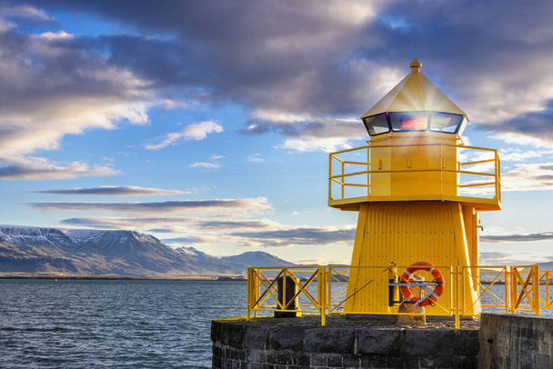 Yellow lighthouse in Reykjavik harbour at sunrise. Early morning with snow covered mountains in the distance. Iceland.  - Fotoğraf, Görsel