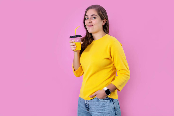 A young woman with orange juice in the pink background - 写真・画像