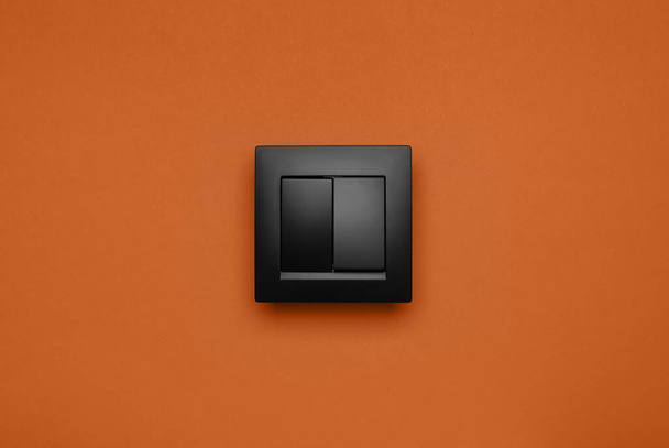 Black plastic light switch on orange background - Foto, afbeelding