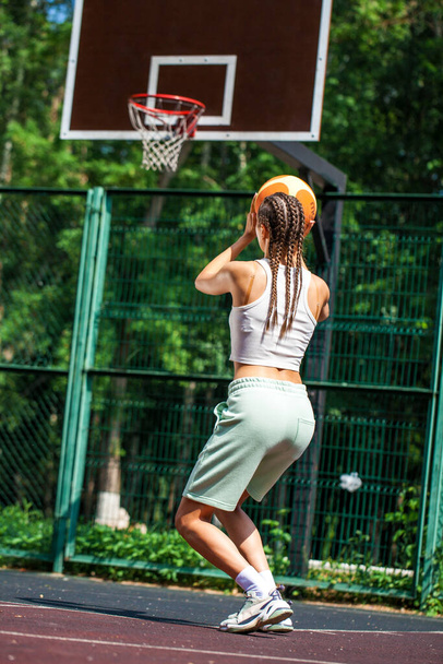 Young beautiful brunette girl posing on the basketball court - Photo, image