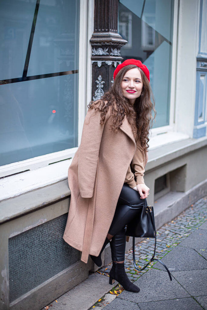 Pretty woman with curly hair in red french beret with windows behind - Valokuva, kuva