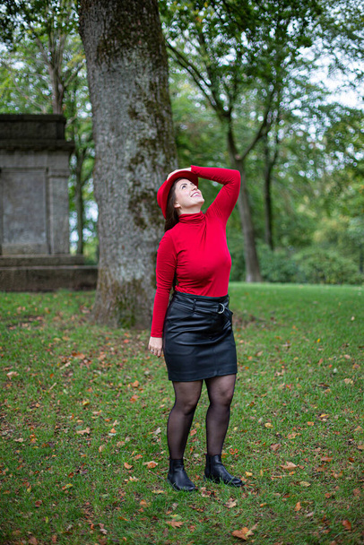 Looking up white woman with long dark hair in bright red in autumn park - Foto, immagini