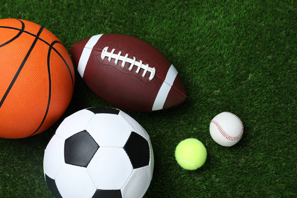 Set of different sport balls on green grass, flat lay - Фото, изображение