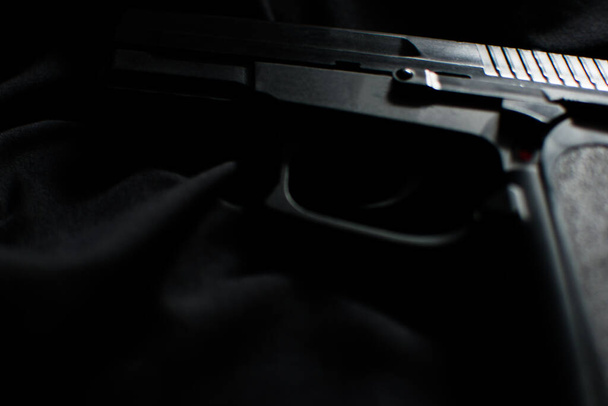 Primer plano de la pistola negra sobre fondo negro. Fotografía de bajo perfil - Foto, Imagen