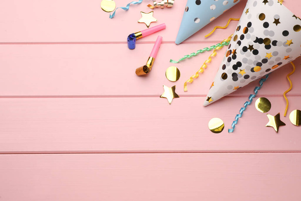 Flat lay composition with party hats, blowers and confetti on light pink wooden background. Space for text - Zdjęcie, obraz
