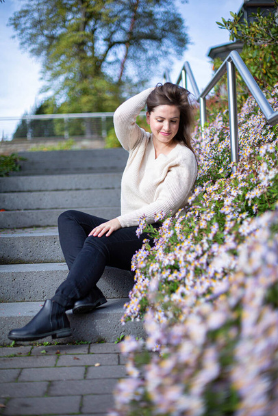 White european woman in sweater near flowers in spring - Foto, Imagen
