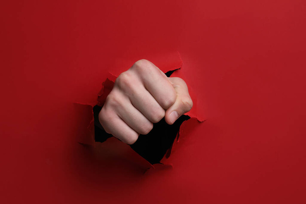 Man breaking through red paper with fist, closeup - Photo, Image