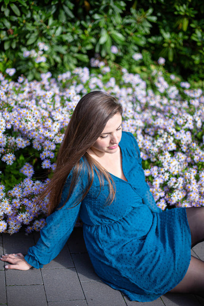 White young european woman near flowers in bright blue - Photo, image