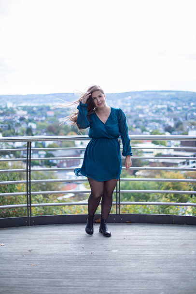 Fehér fiatal európai nő a város mögött fényes kék ruhában - Fotó, kép