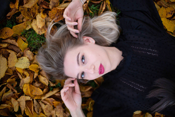 White young european woman in black sweater portrait in fall foliage - Foto, afbeelding